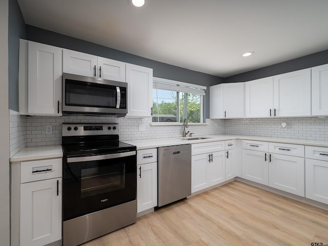 kitchen with light wood finished floors, light countertops, a sink, and appliances with stainless steel finishes