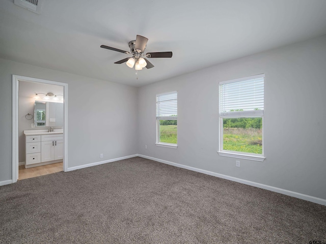 unfurnished bedroom with light colored carpet, baseboards, visible vents, and ensuite bath
