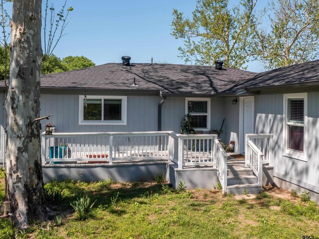 back of property featuring a yard, roof with shingles, and a wooden deck