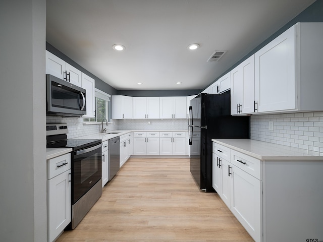 kitchen with light wood-style floors, visible vents, light countertops, stainless steel appliances, and backsplash