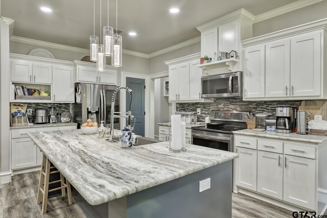 113 Stuart St, Arp, TX 75750 - kitchen featuring stainless steel appliances, tasteful backsplash, a kitchen island with sink, white cabinetry, and ornamental molding
