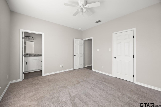 unfurnished bedroom featuring ceiling fan, light colored carpet, sink, and ensuite bath