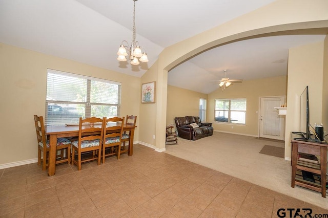 dining area featuring ceiling fan with notable chandelier, light colored carpet, and lofted ceiling