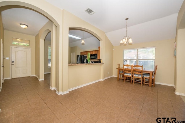 tiled dining area featuring lofted ceiling and an inviting chandelier