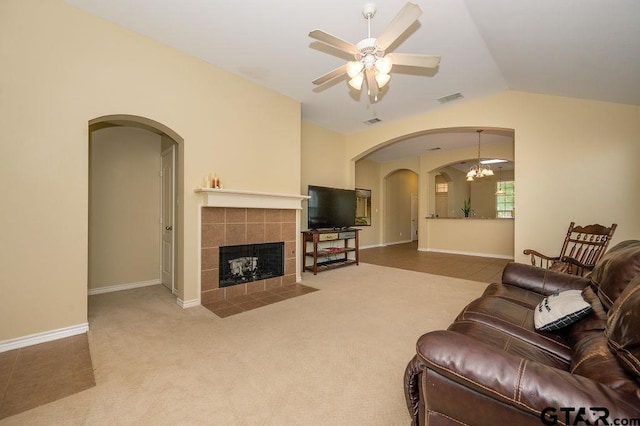 living room with carpet, ceiling fan, lofted ceiling, and a tiled fireplace