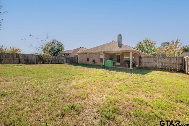 back of property with a lawn and a patio area