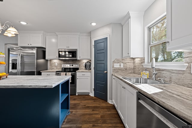 kitchen featuring white cabinetry, stainless steel appliances, decorative light fixtures, and sink