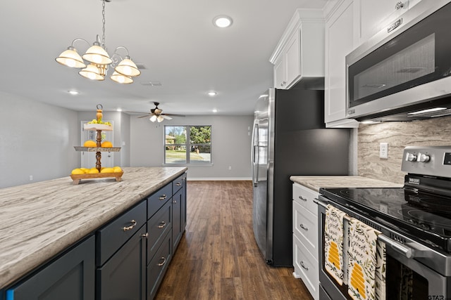 kitchen with white cabinets, dark wood-style flooring, tasteful backsplash, ceiling fan with notable chandelier, and appliances with stainless steel finishes
