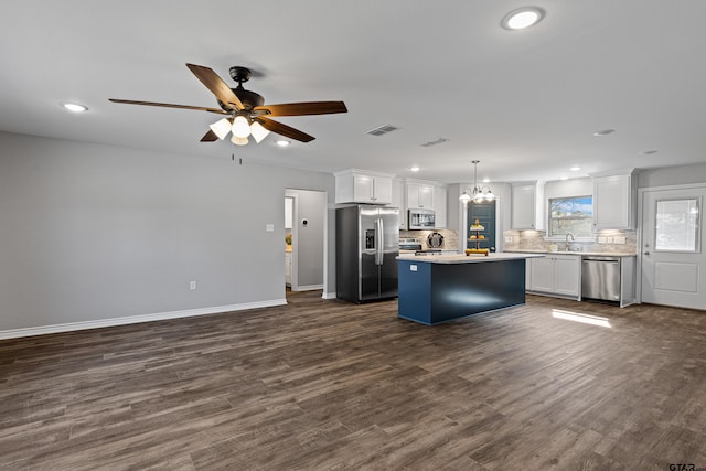 kitchen featuring sink, appliances with stainless steel finishes, white cabinetry, hanging light fixtures, and a kitchen island