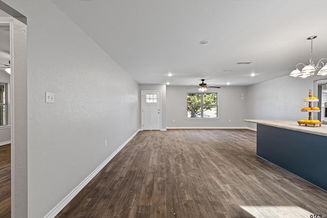 unfurnished living room featuring baseboards, visible vents, dark wood-style floors, and ceiling fan with notable chandelier