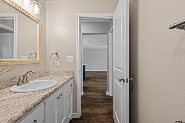 bathroom featuring baseboards, a textured wall, vanity, and wood finished floors