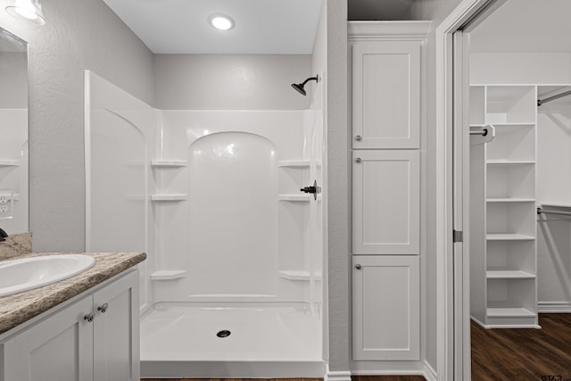 bathroom featuring hardwood / wood-style flooring, vanity, and walk in shower