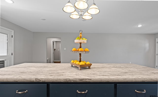 kitchen with blue cabinetry, a center island, and a notable chandelier