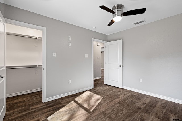 unfurnished bedroom featuring ceiling fan, dark hardwood / wood-style floors, a closet, and a spacious closet