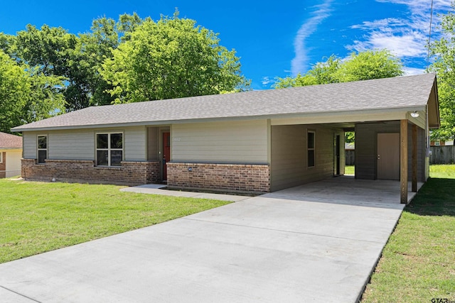 ranch-style home featuring concrete driveway, brick siding, an attached carport, and a front yard