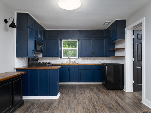 501 S Railroad St, Troup, TX 75789 - kitchen with wooden counters, black microwave, range with gas stovetop, blue cabinetry, and decorative backsplash