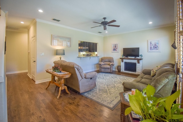 living room featuring hardwood / wood-style floors, ceiling fan, a fireplace, and ornamental molding