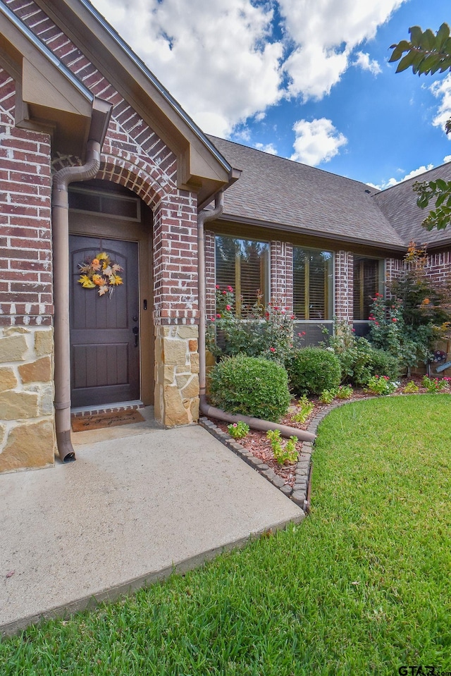 view of exterior entry featuring a lawn