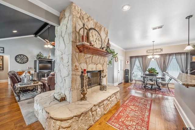 living area with baseboards, wood-type flooring, visible vents, ceiling fan with notable chandelier, and crown molding