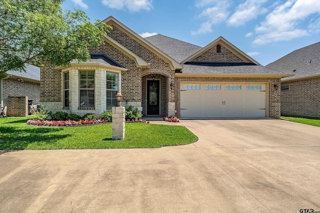 french country style house featuring concrete driveway, brick siding, a garage, a front lawn, and roof with shingles