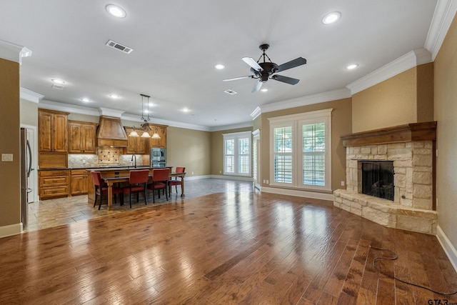 living area featuring baseboards, recessed lighting, light wood-style flooring, ceiling fan, and a stone fireplace