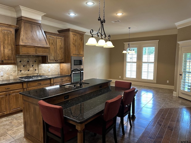 kitchen with a sink, appliances with stainless steel finishes, a breakfast bar area, an island with sink, and tasteful backsplash