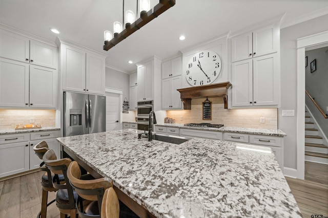 14607 Reserve Ct, Tyler, TX 75707 - kitchen with stainless steel appliances, recessed lighting, light wood finished floors, decorative backsplash, and a center island with sink