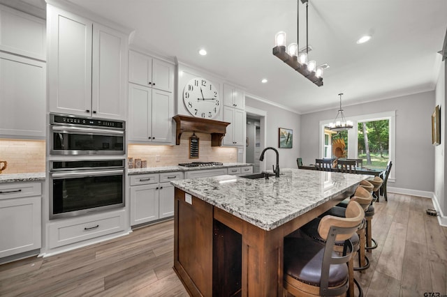 14607 Reserve Ct, Tyler, TX 75707 - kitchen with a chandelier, crown molding, stainless steel appliances, decorative backsplash, and light wood-style flooring