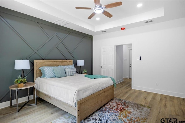 bedroom with visible vents, baseboards, and wood finished floors
