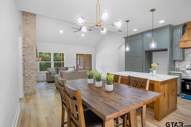 dining space with recessed lighting, arched walkways, an inviting chandelier, and light wood-style floors