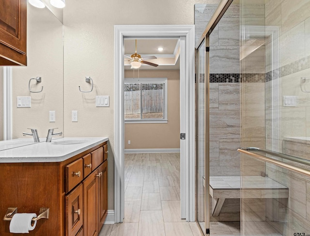 bathroom with vanity, an enclosed shower, ceiling fan, a raised ceiling, and crown molding