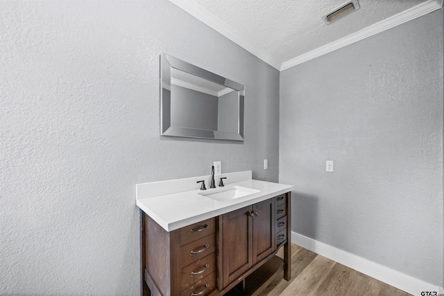 bathroom featuring vanity, ornamental molding, a textured ceiling, and hardwood / wood-style flooring