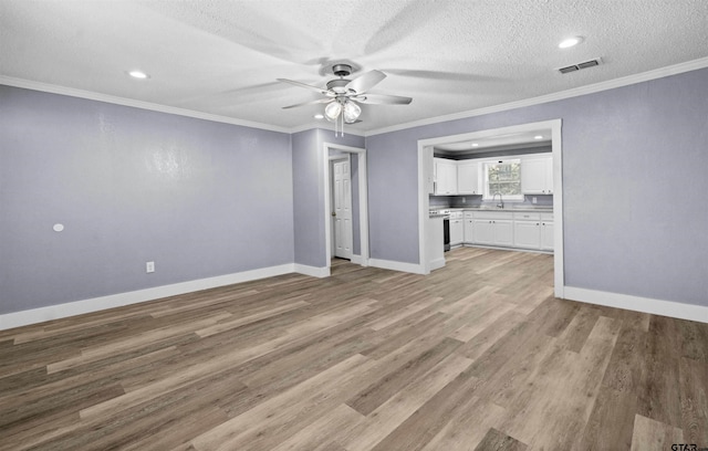 unfurnished living room with ceiling fan, sink, crown molding, light hardwood / wood-style floors, and a textured ceiling