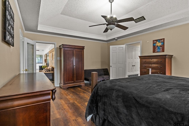 1801 N Fairway, Mount Pleasant, TX 75455 - bedroom with a tray ceiling, dark wood-style flooring, crown molding, a textured ceiling, and a ceiling fan
