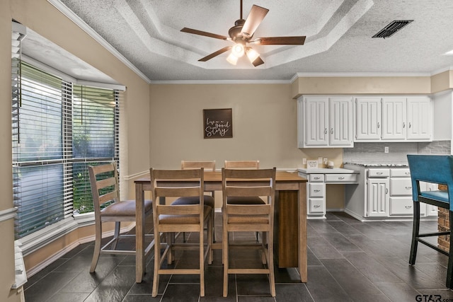 1801 N Fairway, Mount Pleasant, TX 75455 - dining space with a ceiling fan, a textured ceiling, a raised ceiling, crown molding, and dark tile patterned flooring