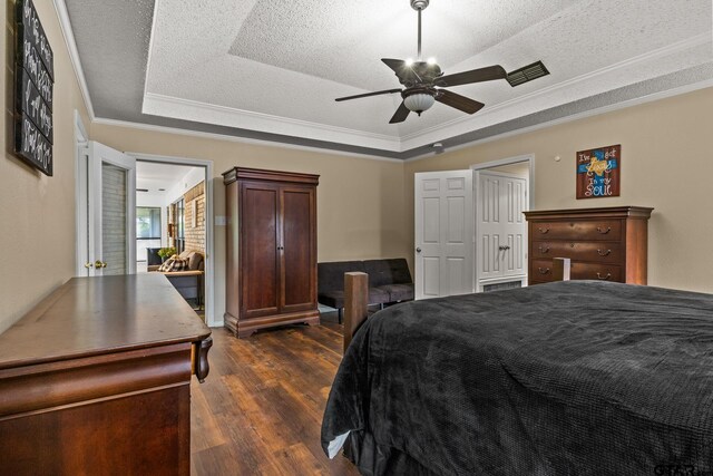 1801 N Fairway, Mount Pleasant, TX 75455 - bedroom with a tray ceiling, dark wood-style flooring, crown molding, a textured ceiling, and a ceiling fan