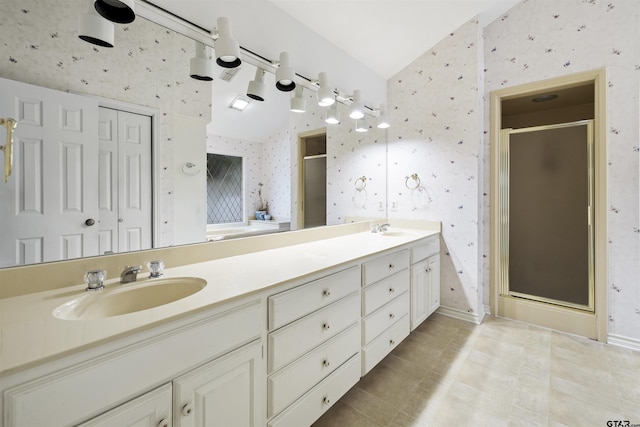 bathroom featuring wallpapered walls, a stall shower, double vanity, and lofted ceiling