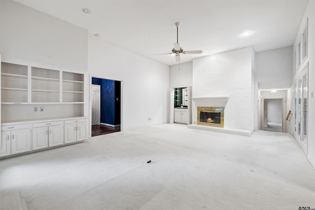 unfurnished living room with ceiling fan, carpet flooring, and a large fireplace