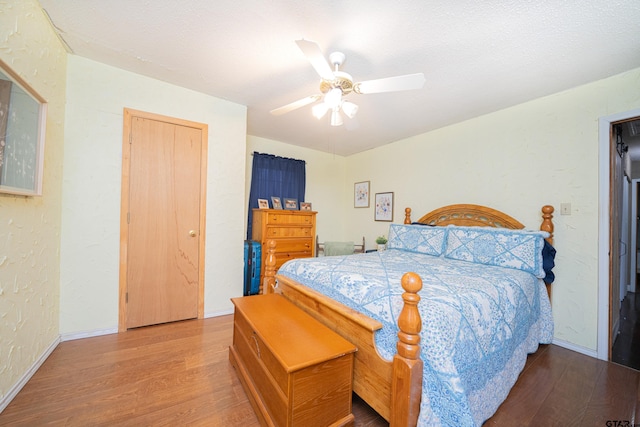 bedroom with hardwood / wood-style floors, ceiling fan, and a textured ceiling