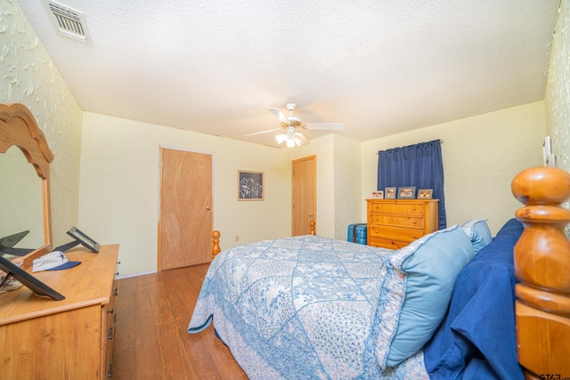 bedroom with a textured ceiling, hardwood / wood-style flooring, and ceiling fan