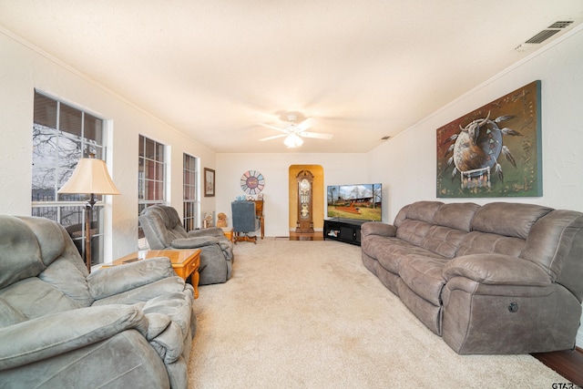 living room with ceiling fan, ornamental molding, and carpet flooring