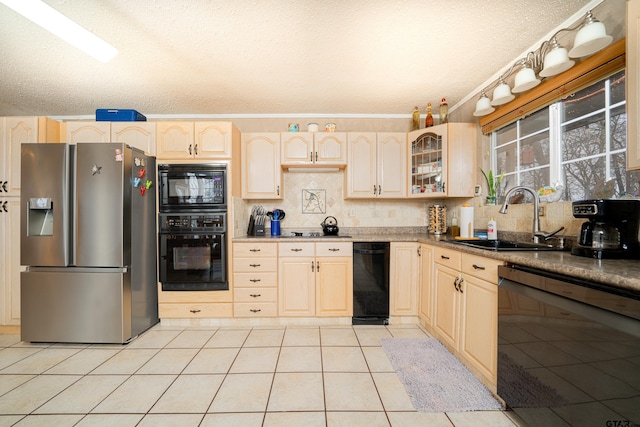 kitchen featuring sink, light tile patterned flooring, a textured ceiling, black appliances, and tasteful backsplash