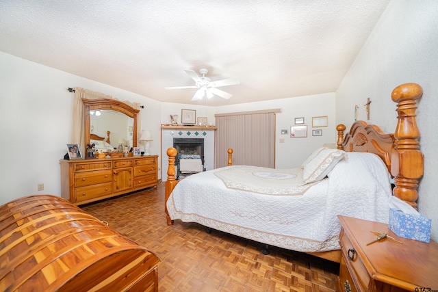 bedroom featuring a textured ceiling, a tiled fireplace, parquet floors, and ceiling fan