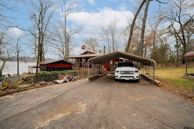 view of parking / parking lot with a water view and a carport