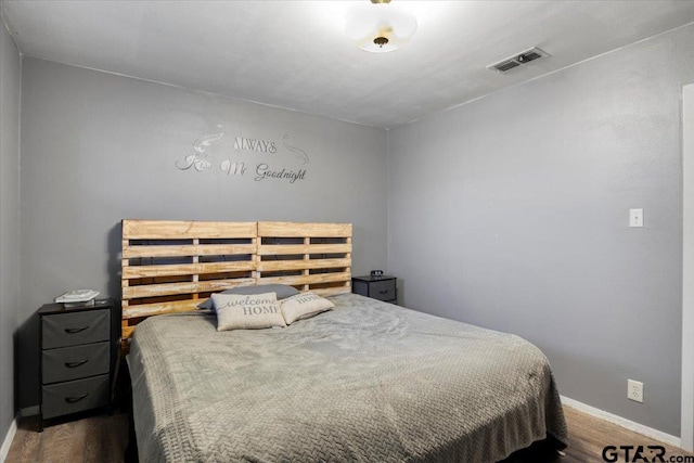 bedroom with wood finished floors, visible vents, and baseboards