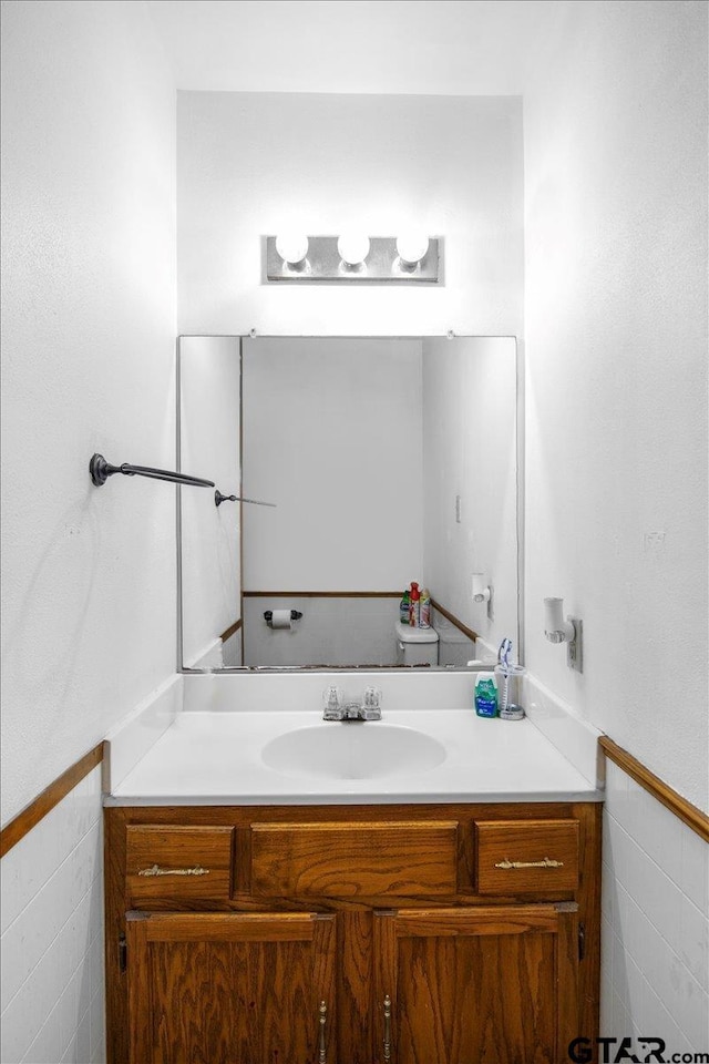 bathroom featuring tile walls, a wainscoted wall, and vanity