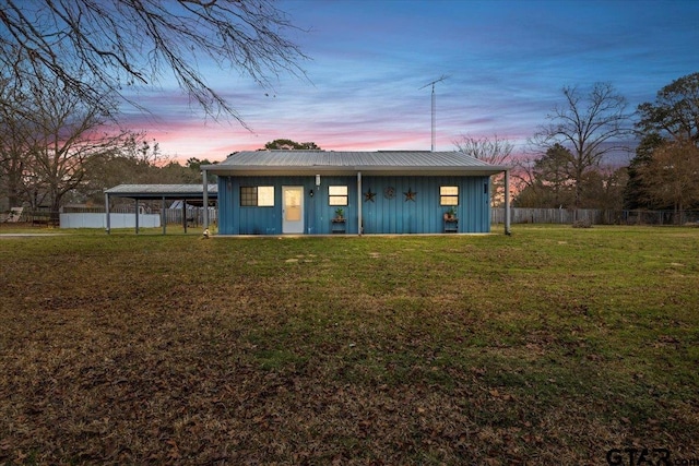 exterior space featuring metal roof, fence, a carport, a front lawn, and board and batten siding