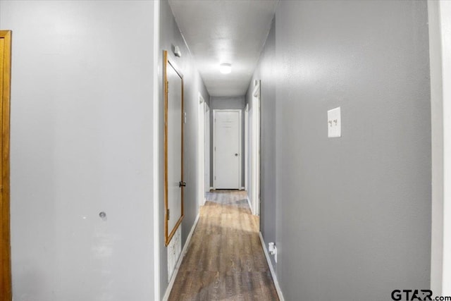 hall with baseboards and wood finished floors