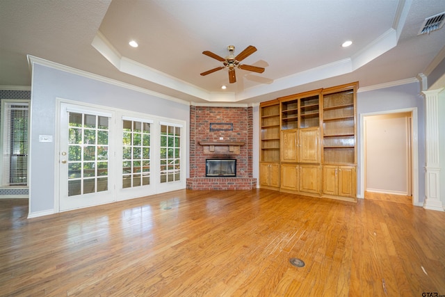 9211 Elm Tree Cir, Tyler, TX 75703 - unfurnished living room featuring a raised ceiling, a ceiling fan, crown molding, light wood finished floors, and a fireplace