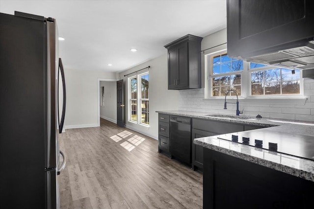 kitchen featuring light stone counters, backsplash, light wood-style flooring, a sink, and black appliances